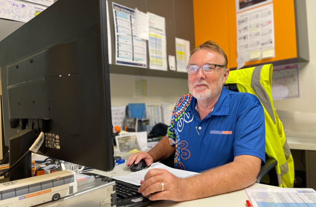 Glenn Neaves sitting at desk looking at his computer monitor and using a mouse 